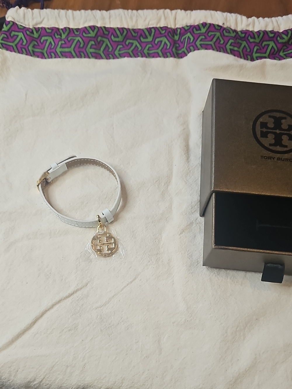 Tory Burch Dust Bag And White Leather Bracelet with Gold Logo Charm.